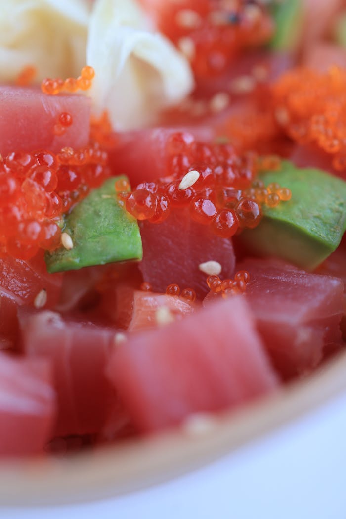 gallery-4 Vibrant sushi poke bowl featuring tuna, avocado, roe, and sesame seeds in a close-up shot.