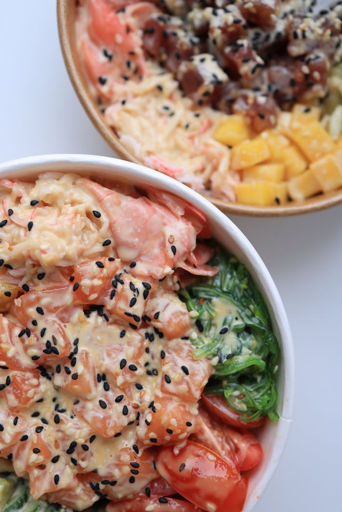 about-01 Delicious poke bowls with fresh salmon, tuna, mango, and seaweed, topped with sesame seeds.