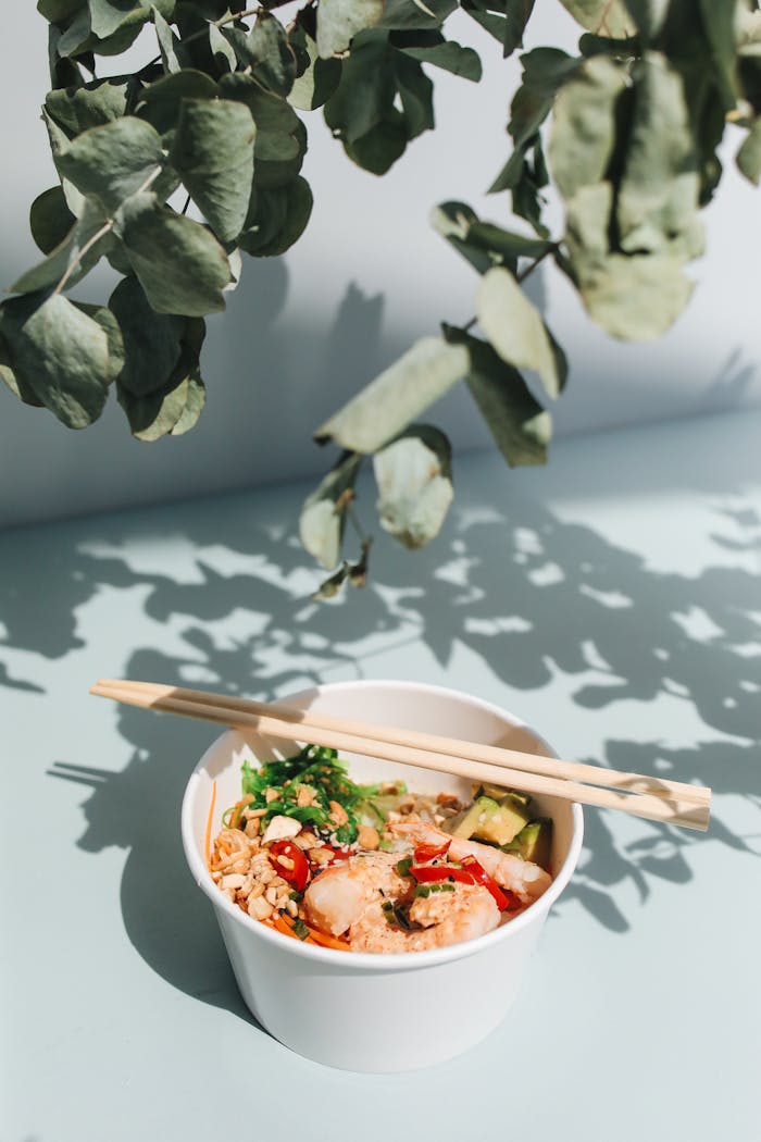 gallery-3 Bright and fresh Hawaiian poke bowl with chopsticks, garnished with avocado and greens. Perfect for food lovers.