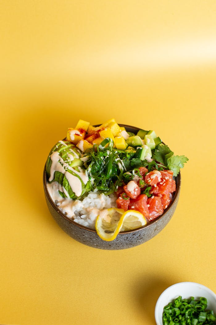 our-experience Colorful Hawaiian poke bowl with fresh ingredients on a vibrant yellow backdrop.